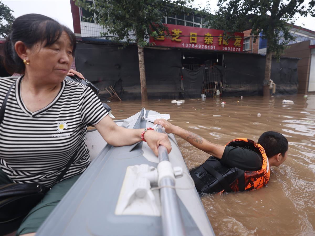 救援队队员跳入水中拉着皮划艇将受困居民转移到安全位置——陶冉 摄